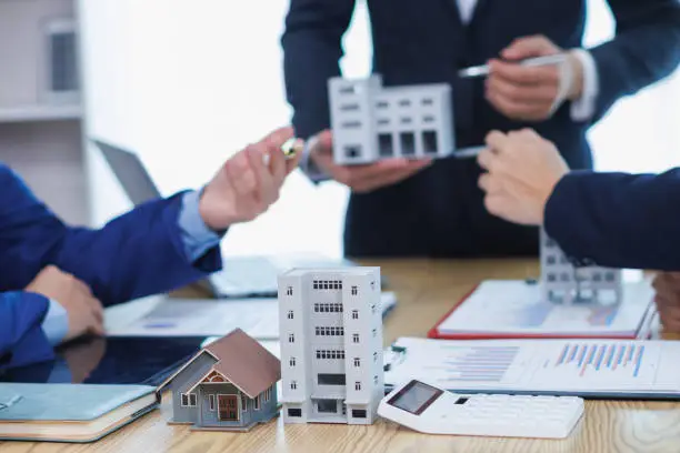 Real estate agents discussing property models and plans